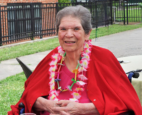 Peace Care resident wearing red and sitting outside smiling